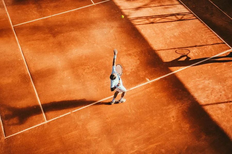 A tennis player serving on a clay court